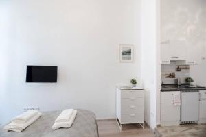 a white bedroom with a bed and a kitchen at Modern studio with AirCon and balcony in the center in Budapest