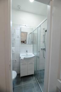 a white bathroom with a sink and a shower at Modern studio with AirCon and balcony in the center in Budapest
