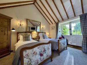 una camera con due letti, uno specchio e una finestra di Guiting Guest House a Guiting Power