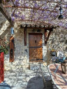 a stone house with a wooden door and a patio at La maison Chabert in Ailhon +3 photos