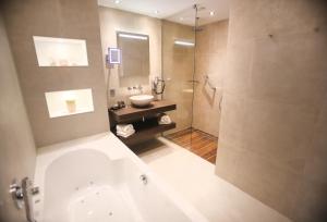 La salle de bains est pourvue d'une baignoire, d'un lavabo et d'une douche. dans l'établissement Van der Valk Hotel Oostzaan - Amsterdam, à Oostzaan