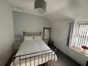 Un dormitorio con una cama y dos ventanas. en Penmaenmawr Coastal Retreat, en Penmaen-mawr