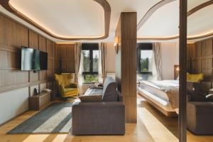 una camera da letto con un letto, un divano e una TV di Hotel Rezident a Žabljak