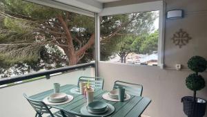 a green table and chairs on a balcony with a window at Le zéphyr in Gruissan