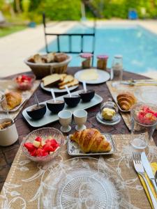 a table with pastries and bowls of fruit on it at Maison des Bourgades in Saint-Julien-de-Peyrolas