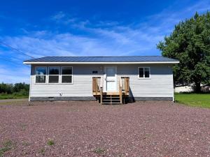 a small white house with a porch on a driveway at 2 bedroom house close to trails in Bergland