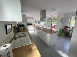 a large kitchen with white cabinets and a sink at Sleeps14- 5Acres- PetFriendly- NearToNormandyCoast in Feugères