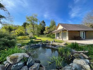 a house with a pond in the yard at 6Bed-Sleeps12-GroupRetreat-YogaStudio-PetFriendly in Feugères