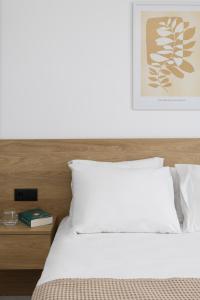 a bed with white sheets and a picture on the wall at Aphrodite in Kallithea Halkidikis