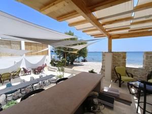 an outdoor patio with tables and chairs and the beach at Phil Samosflats Beachfront Maisonettes in Potokáki