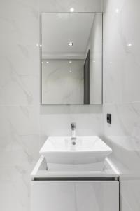 a white bathroom with a sink and a mirror at Aphrodite in Kallithea Halkidikis