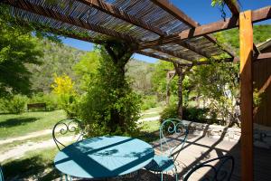 a patio with a table and chairs under a pergola at Les Planious in LʼÉpine