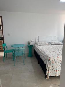 a bedroom with a bed and a table and chairs at Loft mobiliado no centro de Guarapari in Guarapari +2 photos