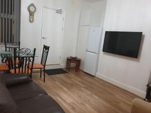 een woonkamer met een bank en een televisie aan de muur bij Cosy Family Flat in Elswick