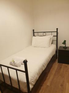 een slaapkamer met een bed met witte lakens en een nachtkastje bij Cosy Family Flat in Elswick +2 foto's