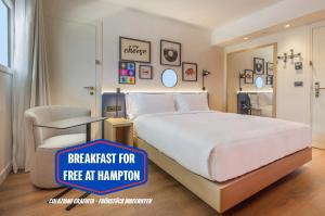 洛索内Hampton By Hilton Locarno的卧室里有一张白色的大床和一把椅子