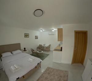 a white bedroom with a bed and a kitchen at The River Studio Beli in Podgorica
