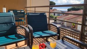 a balcony with two chairs and a table with fruit at Résidence Saphir avec piscine et climatisation in Collioure