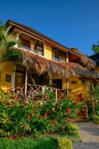 a yellow house with a straw roof at Banana Palms Hotel in Rio Dulce