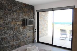 a living room with a brick wall and a sliding glass door at Astrokastro Frangokastello in Frangokastello