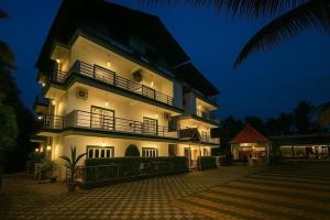 a large white building with a balcony at night at Golden Rice Resort & Cottages in Candolim