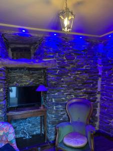 a room with a stone wall with a chair and a tv at Séjournez dans la Tour ! in Ploërmel
