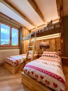 two beds in a room with wooden walls and windows at Casa Clus Bormio apartments 3 in Valdisotto