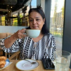 una mujer sentada en una mesa bebiendo de un tazón en Nama-Stay Harrogate, en Harrogate