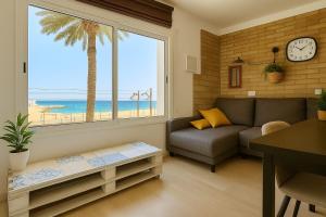 a living room with a couch and a palm tree at La Bellamar - Apartamento en primera línea mar- in Premiá de Mar