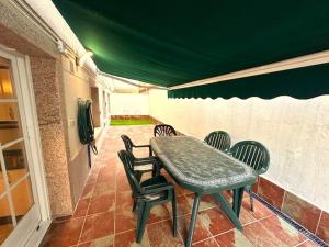 a table and chairs on a patio with a green roof at Apartamento Welcome Grañamar in Sanxenxo