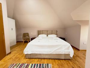 a bedroom with a large white bed and a chair at GenAl Apartaments in Tirana