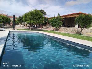 a swimming pool in front of a house at Tapada das Carvalhas in Castelo Branco