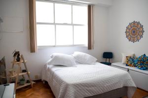 a bedroom with a bed with white sheets and a window at Apto Centro do Rio - Cinelândia - Consulado Americano - Vivo Rio - 1 min Metrô in Rio de Janeiro