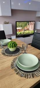 a wooden table with two green plates and a tv at Ekskluzywny Apartament w Centrum z Klimatyzacją i Balkonem in Lubin