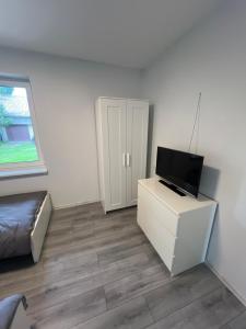 un salon avec une télévision sur un meuble blanc dans l'établissement Pušų Sodas, à Birštonas