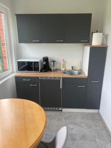 une cuisine avec des armoires noires et une table en bois dans l'établissement Pušų Sodas, à Birštonas