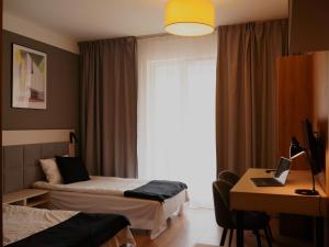 a hotel room with two beds and a desk with a laptop at Warsoliv Apartament premium in Warsaw
