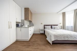 a white bedroom with a bed and a kitchen at Baliò Villa in Palanga