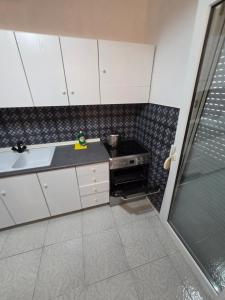 a small kitchen with white cabinets and a stove at iraklitsa house in Iraklitsa