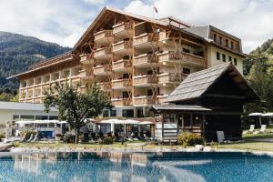 a hotel with a swimming pool in front of it at Thermenwelt Hotel Pulverer in Bad Kleinkirchheim