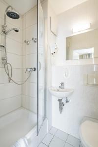 a white bathroom with a shower and a sink at Hotel Pankow in Berlin