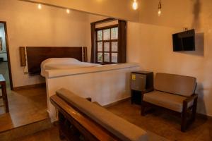 a bedroom with a bed and a chair and a tv at Cotan Ecolodge in La Esperanza