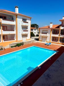a swimming pool in front of a building at Apt T3 - Golf&Surf Praia Del Rei in Amoreira
