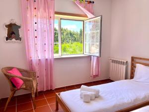 a bedroom with a bed and a window and a chair at Apt T3 - Golf&Surf Praia Del Rei in Amoreira