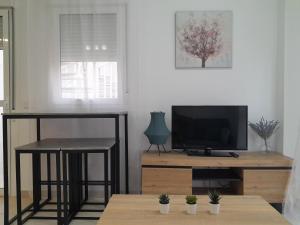 a living room with a tv and a table with stools at Preciso atico con jacuzzi en Laguna Beach in Vera