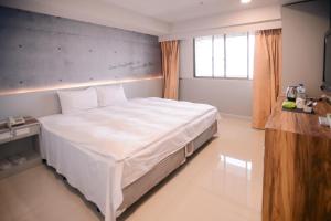 een slaapkamer met een groot wit bed in een kamer bij KIWI-Taichung Station Branch 1 in Taichung