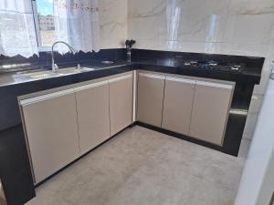 a kitchen with white cabinets and a sink at Casa aconchegante in São Thomé das Letras