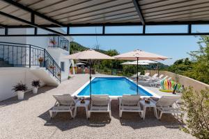 a swimming pool with chairs and umbrellas next to a building at House with Pool - Ratisevina in Herceg-Novi