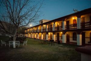 a lit up building with tables and chairs in front of it at Hotel El Nogalito in Cuatrociénegas de Carranza
