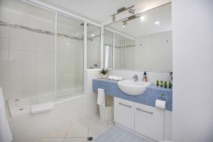 a white bathroom with a sink and a shower at Tropical Comfort Pool and Stunning Esplanade in Cairns +20 photos